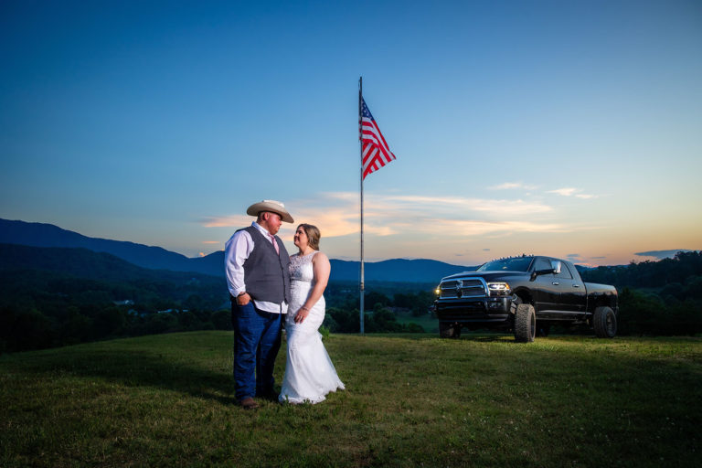 A couple stands in front of an American during sunset at their Harper's Vineyard wedding.